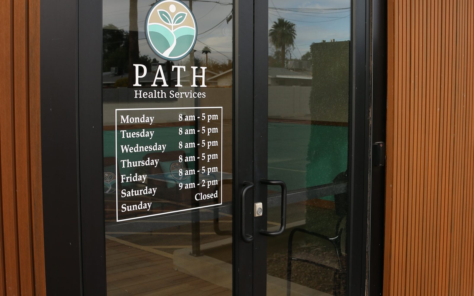 The front door of PATH Health Services at 605 E Broadway Rd, with the PATH logo and opening hours on the glass
